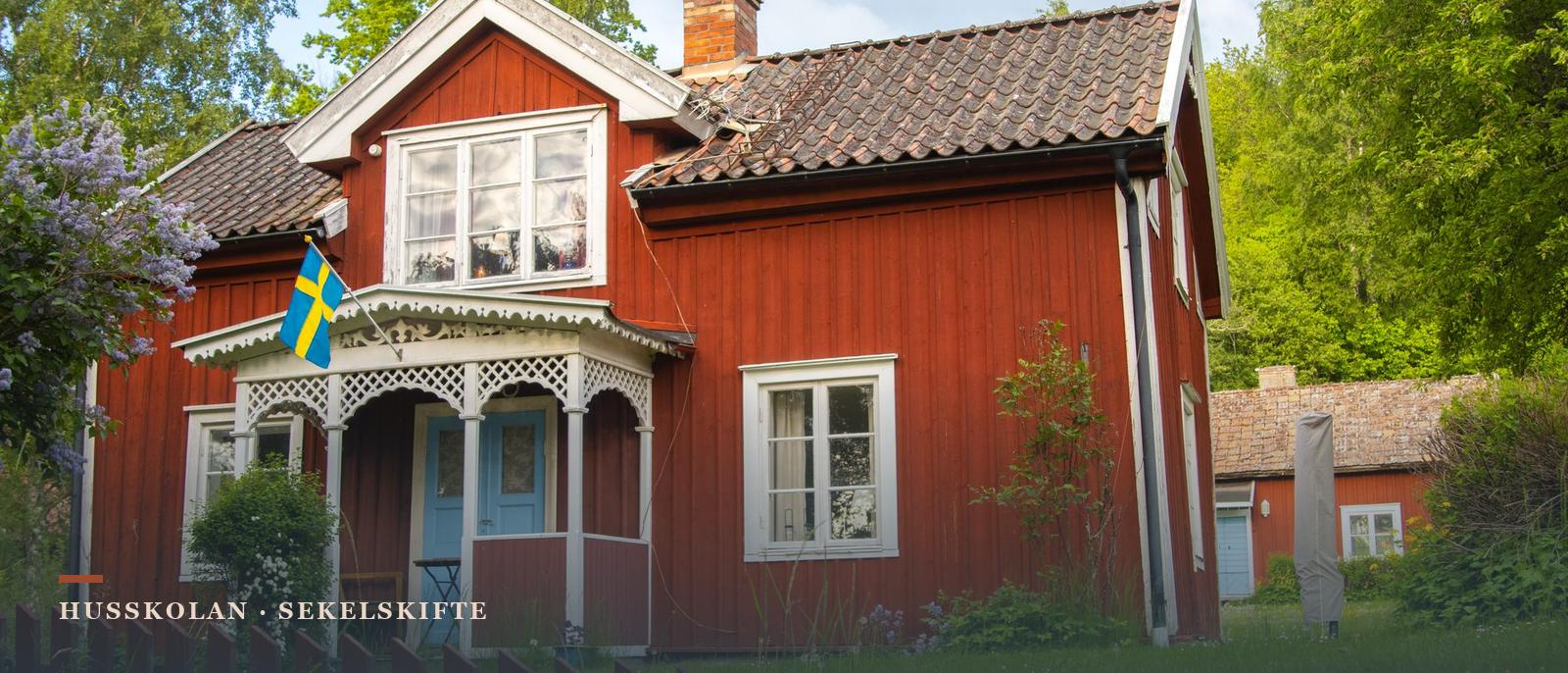 Faluröd trävilla i 1½ plan med snickarglädje på verandan, frontespis och spröjsade fönster