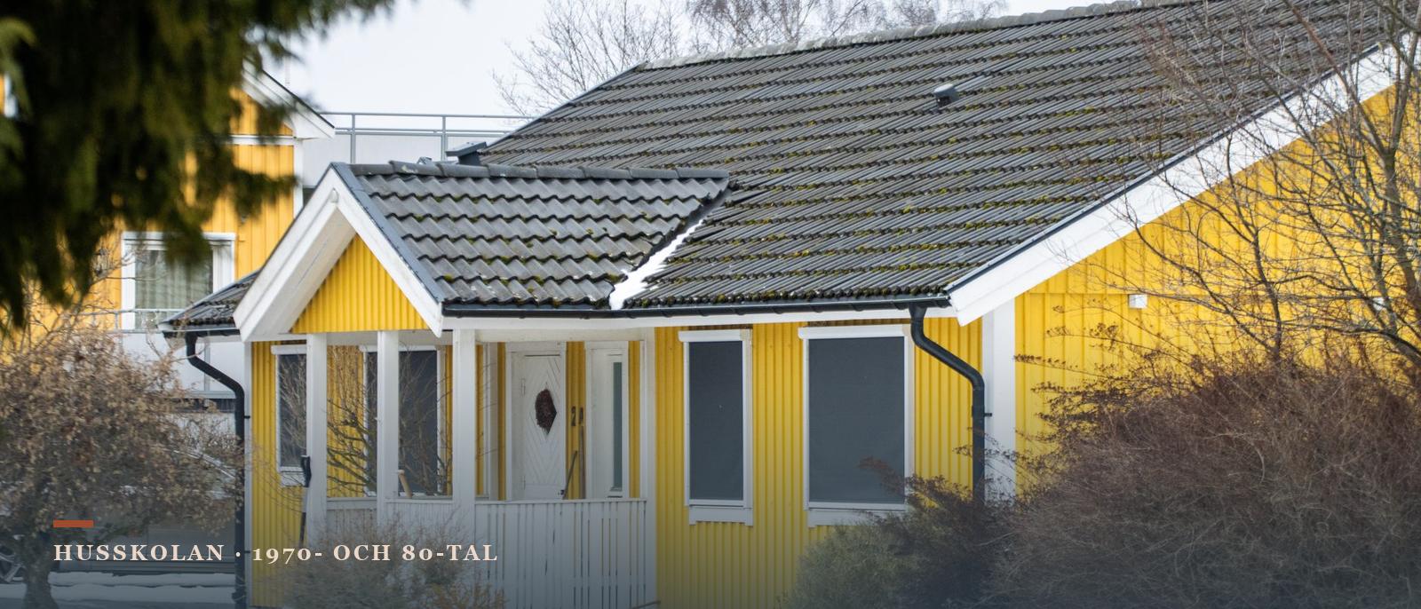 Gult enplanshus med stående träpanel, betongpannor och entrétak i vinterlandskap